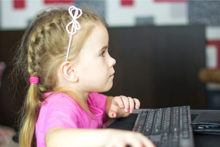 Young child sitting at a computer.