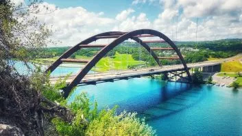A bridge with cars on it crossing over a river.